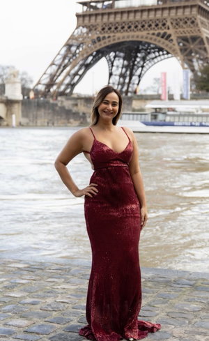 Woman in red sequined dress posing near Eiffel Tower.