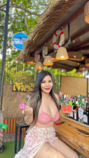 Asian woman in pink bikini and lace skirt at outdoor bar.