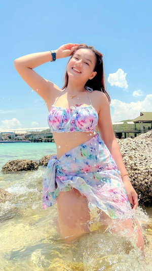 Smiling woman in floral bikini standing in ocean water.