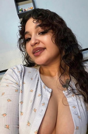 Woman with curly dark hair in floral top indoors.