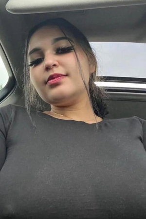 Curvy woman in dark top taking car selfie.