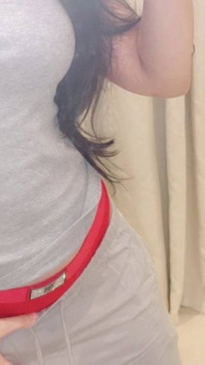 Woman in gray top and red waistband, indoor setting, side view.