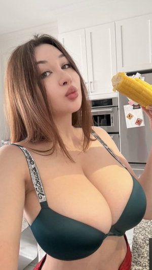 Asian woman in green bra taking selfie in kitchen.