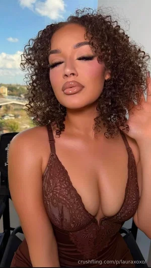 Woman with curly hair in brown lace top, outdoors on balcony.