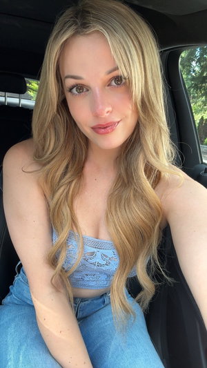 Blonde woman in blue lace top and jeans selfie in car