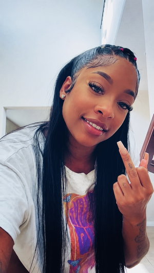 Woman with long black hair and graphic tee making hand gesture indoors.
