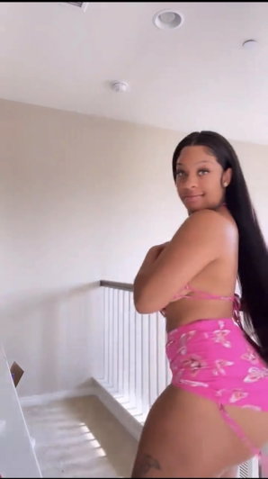 Woman with long dark hair in pink bikini indoors.
