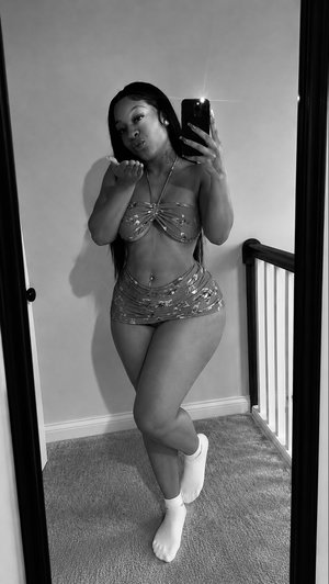 Woman in shiny top and skirt poses in mirror selfie indoors.
