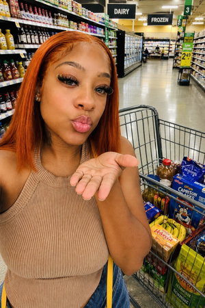 Woman with red hair in beige top posing in grocery store.