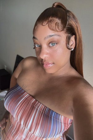 Curvy woman with ponytail wearing striped strapless top indoors.