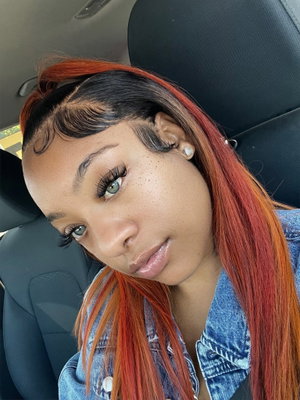 Woman with red and black hair in denim jacket inside car.