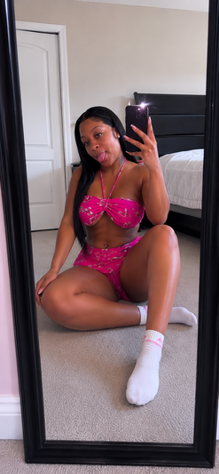 Woman in pink bikini taking mirror selfie in bedroom.