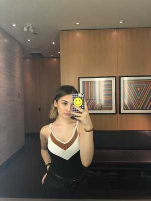 Woman with short brown hair taking indoor selfie in colorblock top.