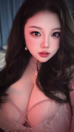 Asian woman with long dark hair in pink lace lingerie indoors.