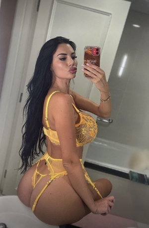 Woman in yellow lingerie taking mirror selfie in bathroom.