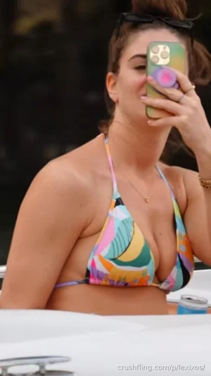 Woman in colorful bikini top taking mirror selfie outdoors.