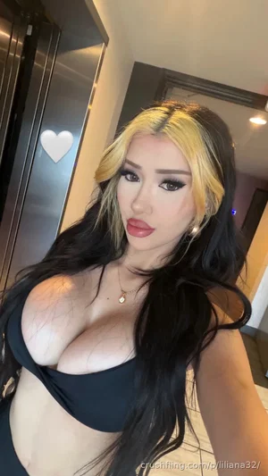 Woman with long black and blonde hair wearing black top, indoors.