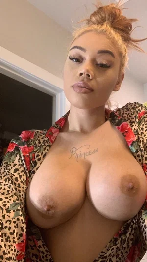 Woman with blonde hair in bun, wearing floral leopard robe, bare chest with visible nipples and