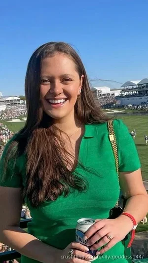 Woman in green top holding a can, smiling at a sunny outdoor event.