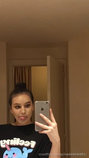 Woman in black graphic t-shirt taking mirror selfie indoors.