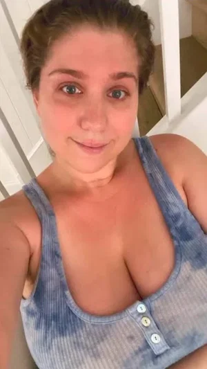 Woman in blue tie-dye tank top, indoor setting, facing camera.
