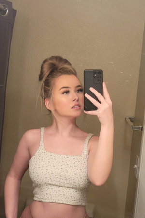 Blonde woman in crop tank top and underwear in bathroom.