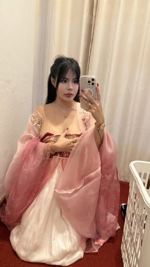 Asian woman in pink dress taking selfie indoors.