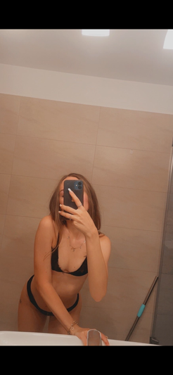 Woman in black lingerie taking mirror selfie in bathroom.