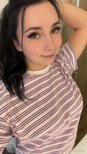 Woman with dark hair in striped shirt posing indoors, hand in hair.