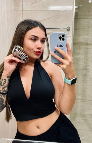 Brunette woman in black halter top taking mirror selfie in bathroom.