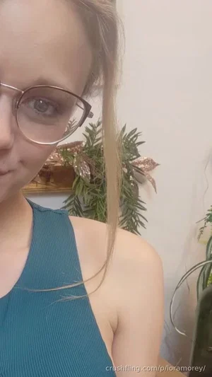 Woman with glasses in teal halter top, indoor setting with plants.