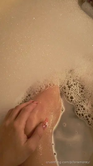 Person's leg and hand in bubbly bathwater, close-up view.