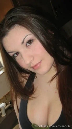 Woman with long dark hair wearing a black top, indoors, close-up selfie.