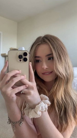 Woman with long blonde hair taking a selfie indoors.