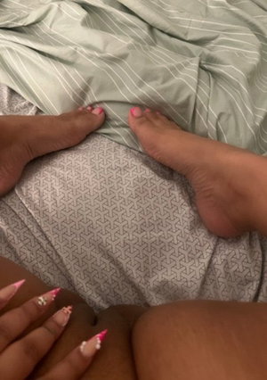 Person with pink nails on bed with striped sheets.