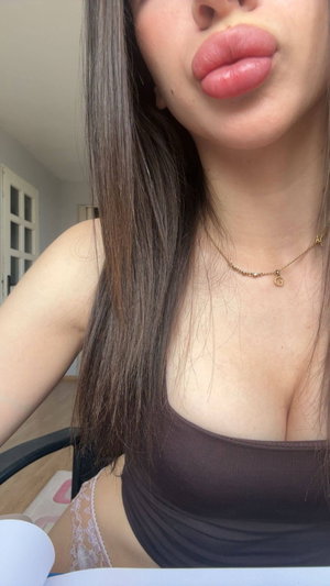 Woman with long dark hair in brown top and necklace indoors.