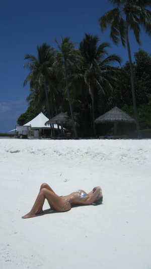Slim woman in silver bikini on beach.