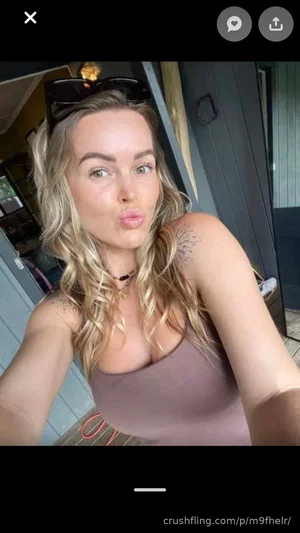 Blonde woman in a brown tank top making a playful face, outdoors near a door.