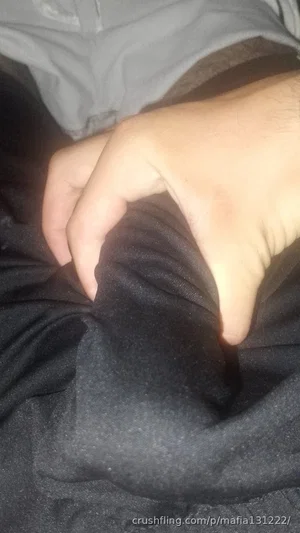 Close-up of a person's hand on dark fabric, wearing a gray top, indoors.
