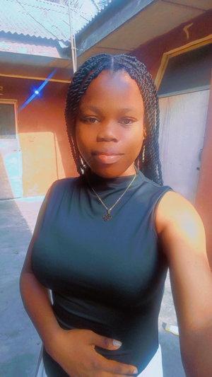 Woman with braided hair in black top taking outdoor selfie.