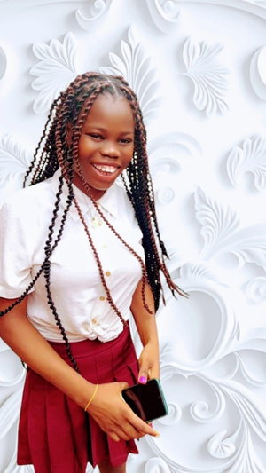 Woman with braids in white shirt and red skirt holding phone.