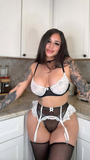 Tattooed woman in lingerie posing in kitchen.