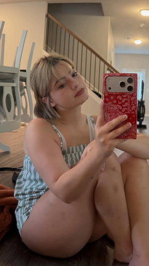 Blonde woman in striped dress taking a selfie indoors.