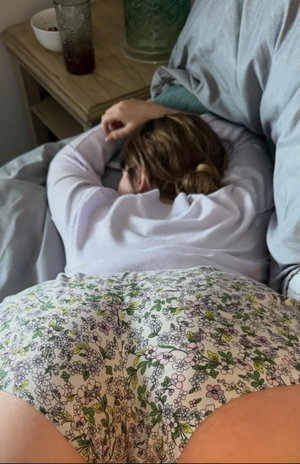 Woman with brown hair in floral shorts lying on bed.