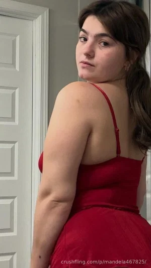 Woman in red dress posing indoors, back to camera, looking over shoulder.