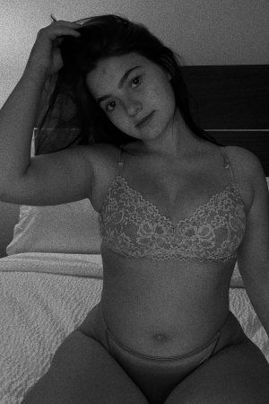 Curvy woman in lace bra and panties on bed.