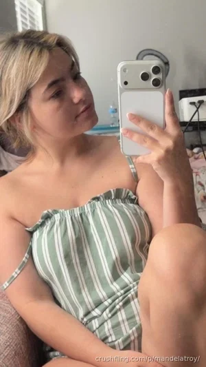 Woman with blonde hair in striped top taking mirror selfie indoors.