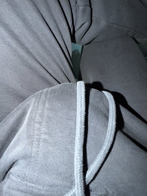Close-up of gray hoodie with drawstrings, partially open to reveal inner clothing.