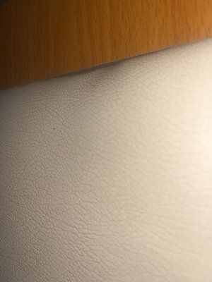 Close-up of textured white surface and wooden edge, no person visible.