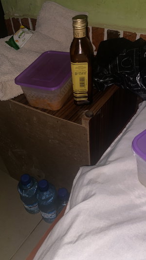 Cluttered indoor shelf with food containers, oil, water bottles.